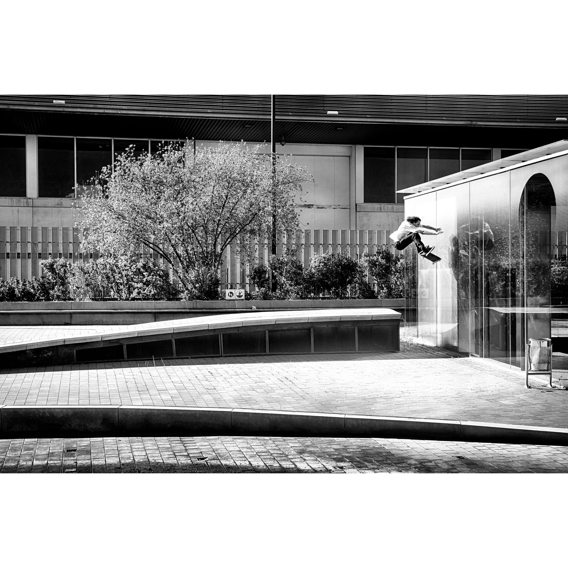 Black and white photo of Evan Smith doing a kick flip wallride in Barcelona Spain. Off bump onto wall.