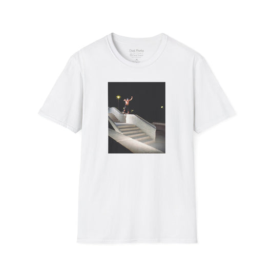 A white crew neck short-sleeve T-shirt featuring a printed photo of A high-quality print featuring an iconic shot of Chad Muska in 1999 executing a smooth nose slide down the triple-kink Hubba rail at The Wedge in Phoenix, Arizona. Captured by photographer David Broach, this image showcases Muska’s signature style and fearless approach, making it a must-have for skateboarding enthusiasts and collectors."