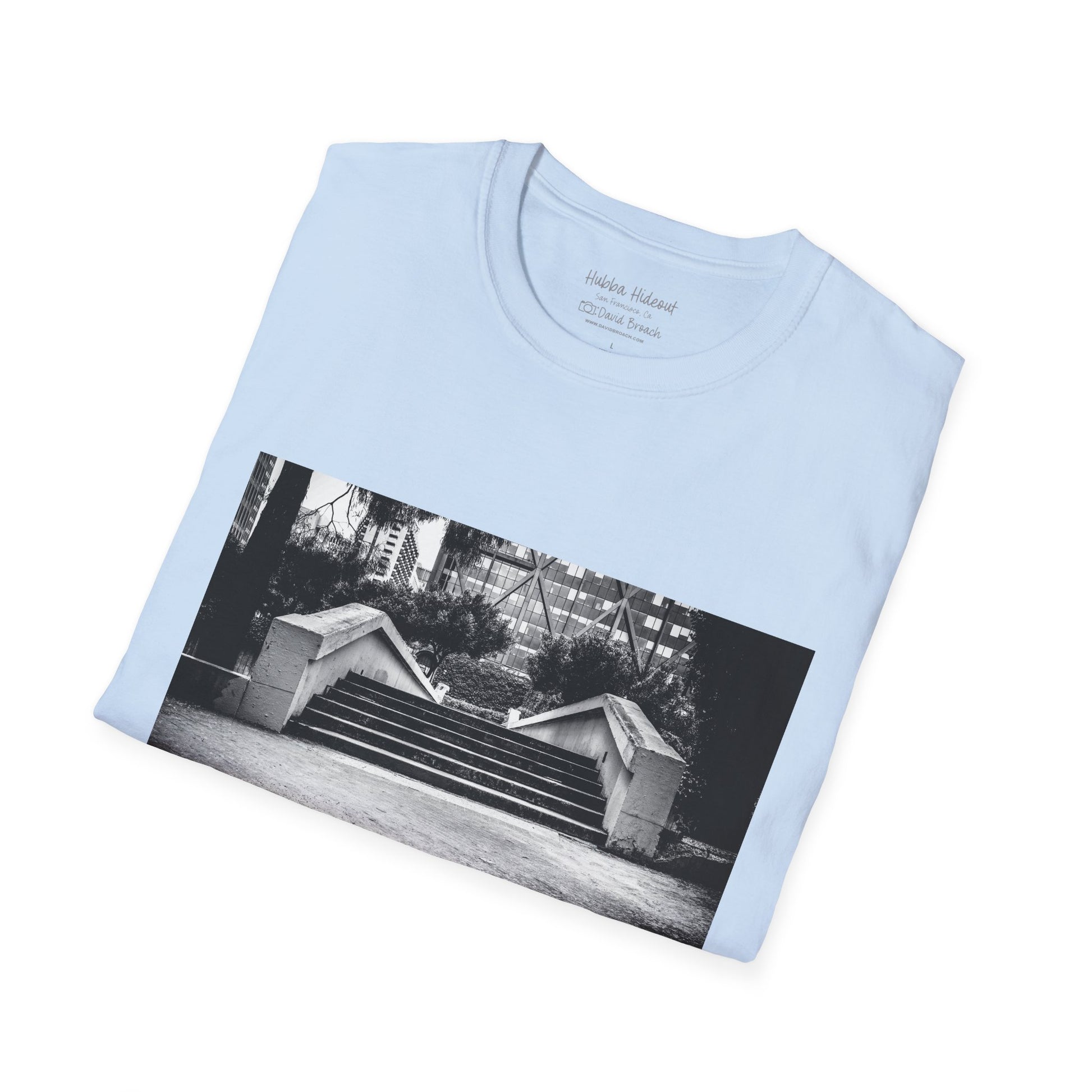 A neatly folded light blue  crew neck short-sleeve T-shirt featuring a printed photo of the iconic Hubba Hideout skate spot on the front. Captured by photographer David Broach, the detailed design highlights the legendary location, making it a must-have for skateboarding enthusiasts and streetwear fans.