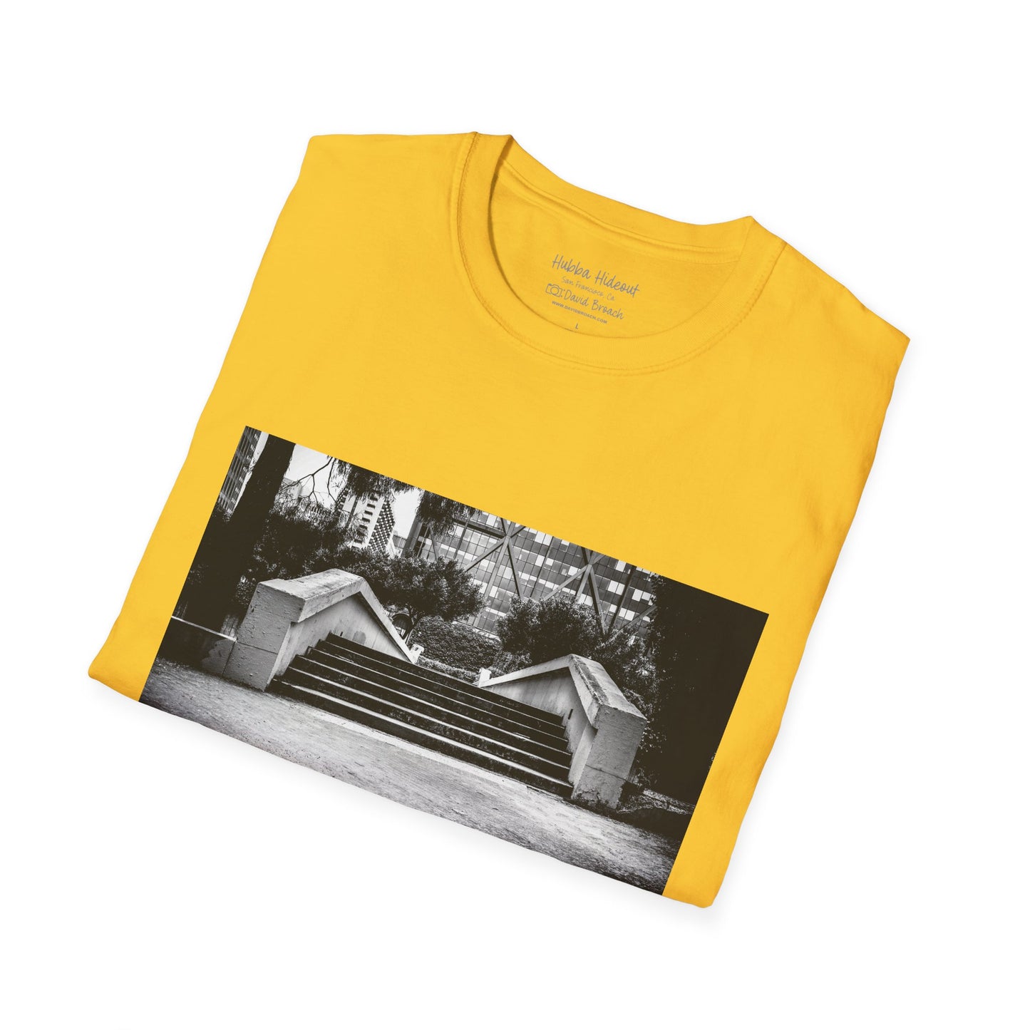 A neatly folded yellow T-shirt featuring a black-and-white photo of the iconic Hubba Hideout skate spot printed on the front. The bold contrast of the monochrome image against the vibrant yellow fabric highlights the design, making it a standout piece for skateboarding enthusiasts and streetwear fans.