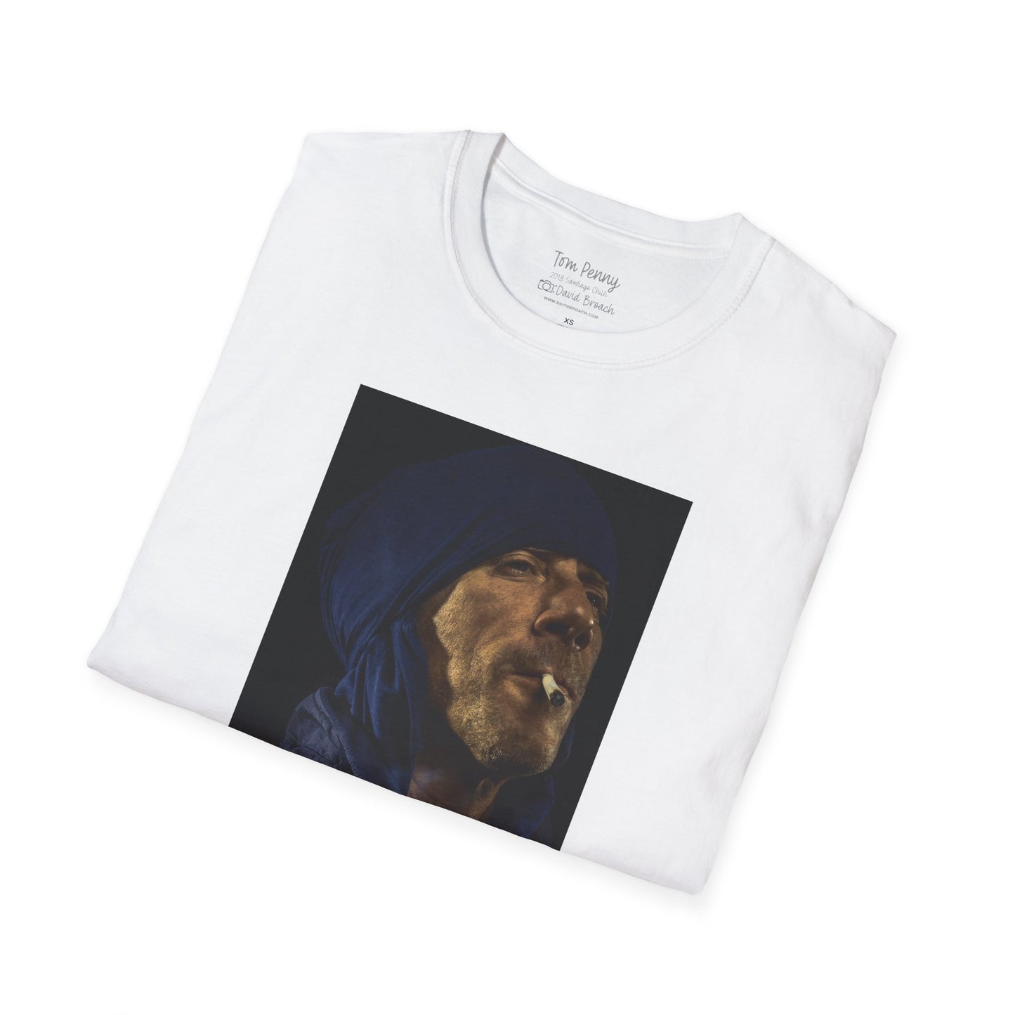 A neatly folded white crew neck short-sleeve T-shirt featuring a printed portrait of legendary pro skater Tom Penny smoking a joint against a black background. Captured by photographer David Broach, the design highlights Penny’s effortless style and mystique, making it a must-have for skateboarding enthusiasts and streetwear fans.