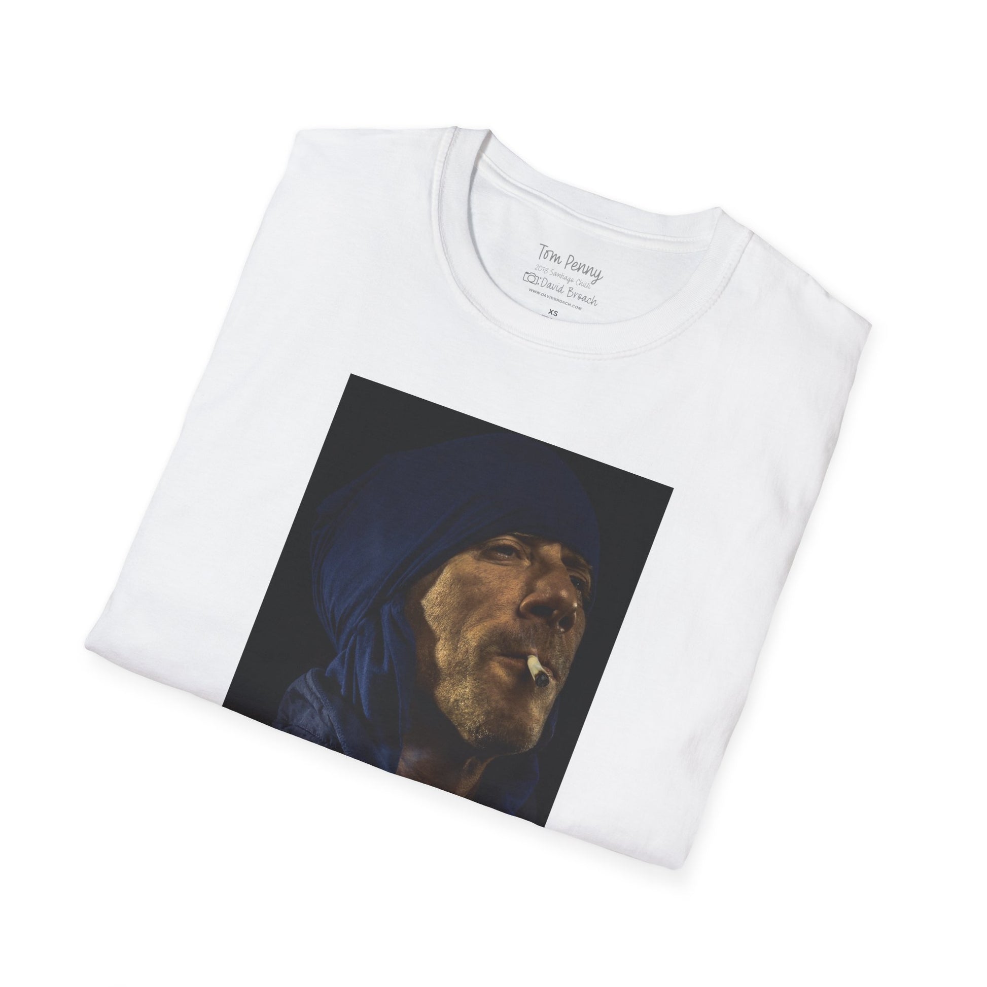A neatly folded white crew neck short-sleeve T-shirt featuring a printed portrait of legendary pro skater Tom Penny smoking a joint against a black background. Captured by photographer David Broach, the design highlights Penny’s effortless style and mystique, making it a must-have for skateboarding enthusiasts and streetwear fans.