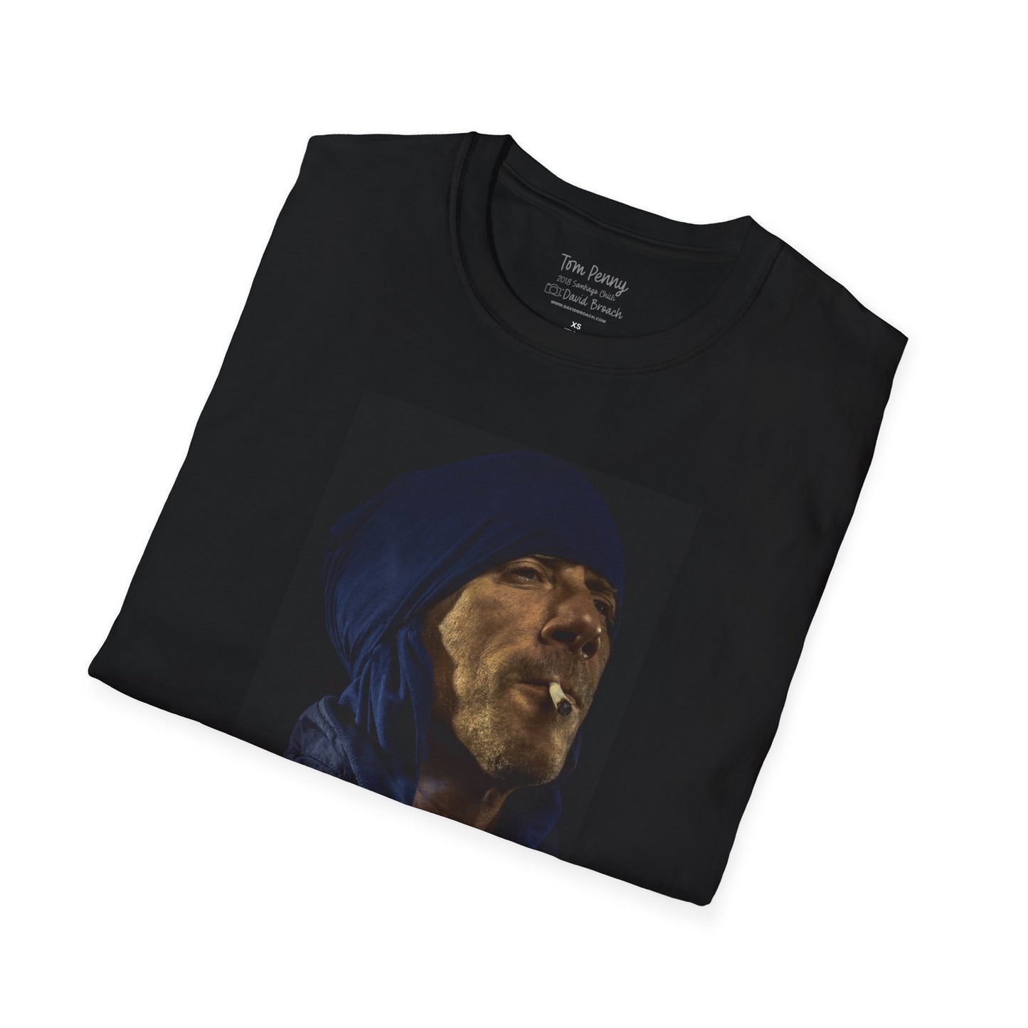 A neatly folded black crew neck short-sleeve T-shirt featuring a printed portrait of legendary pro skater Tom Penny smoking a joint against a black background. Captured by photographer David Broach, the design highlights Penny’s effortless style and mystique, making it a must-have for skateboarding enthusiasts and streetwear fans.